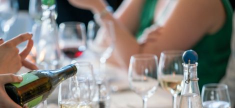 person pouring wine on clear wine glass